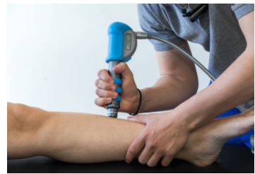 A practitioner performs shockwave to a client's leg
