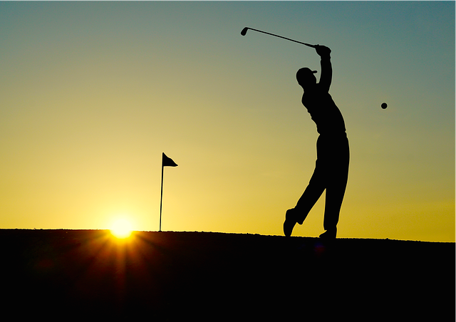 Shadow of golfer hitting ball with sunset behind