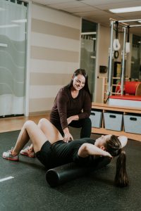 A physio helps show a client in a Vancouver clinic how to foam roll