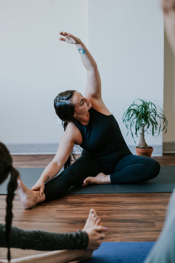 A Woman leads a group through stretches in a yoga type setting